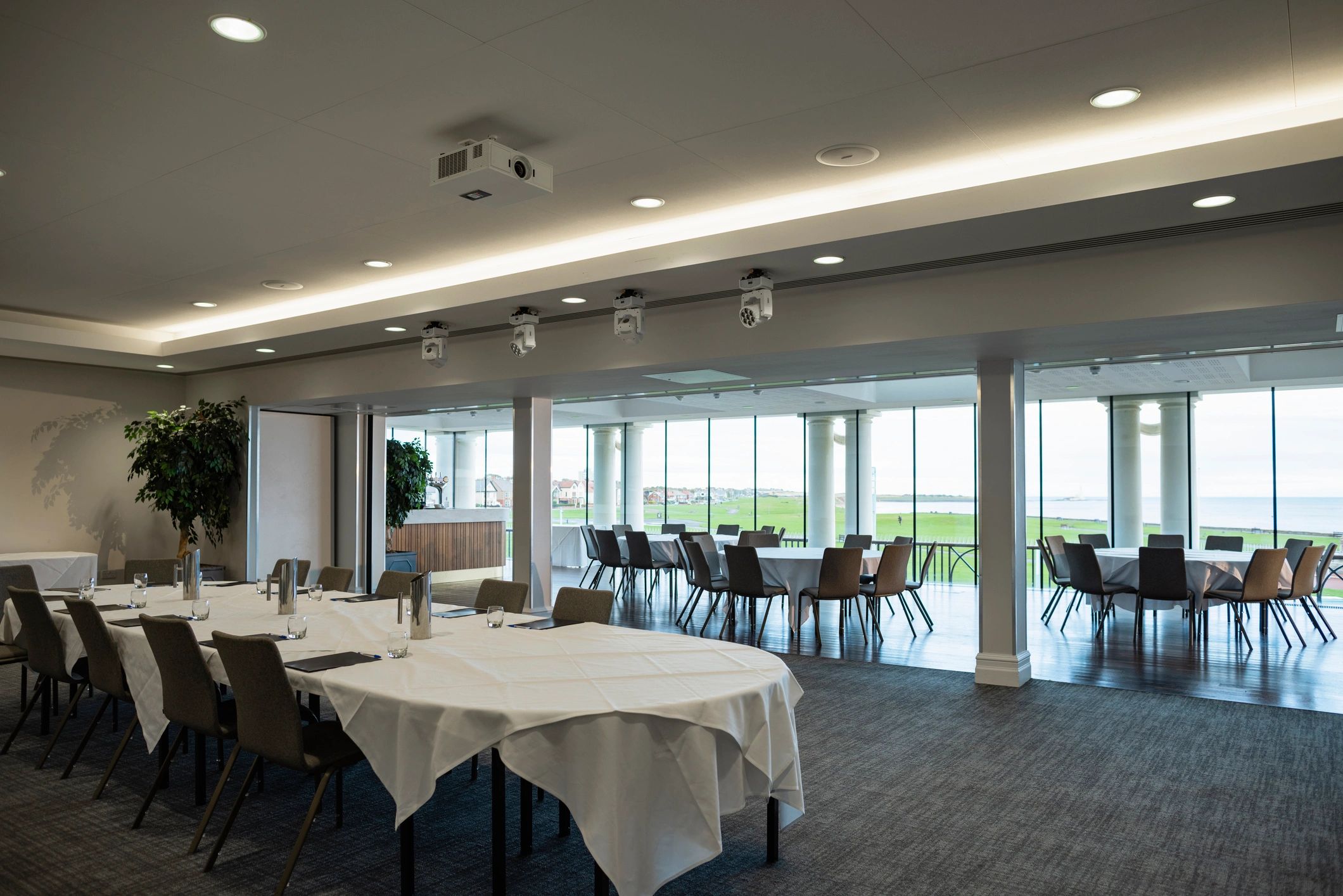 Banquet-style room with round tables and large windows